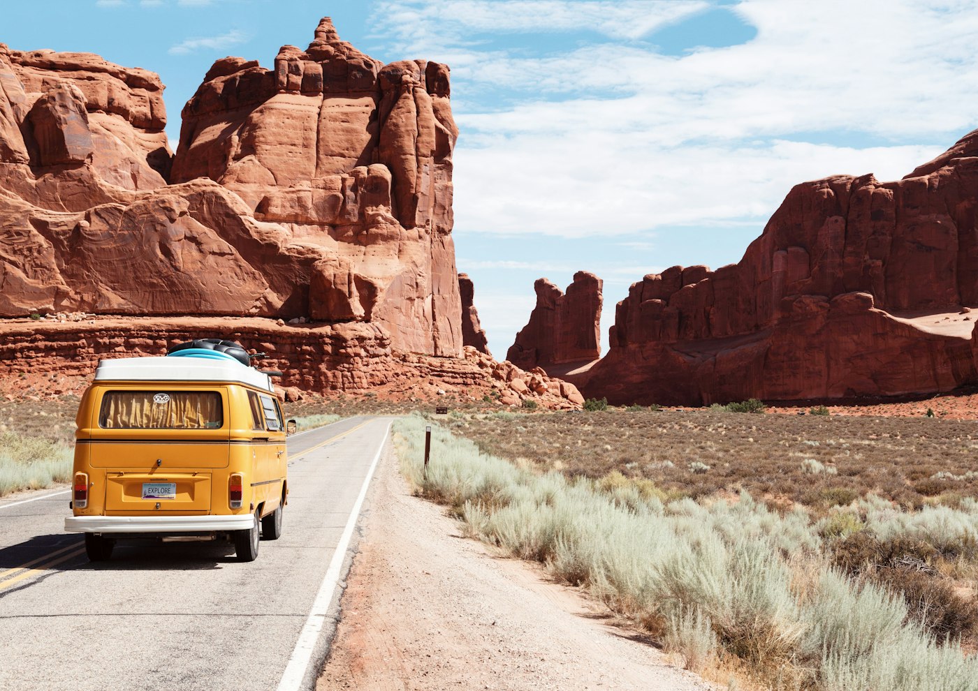 Yellow camper van driving through red rock desert scenery